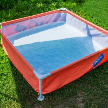A children's pool filled with water stands on the grass in the yard