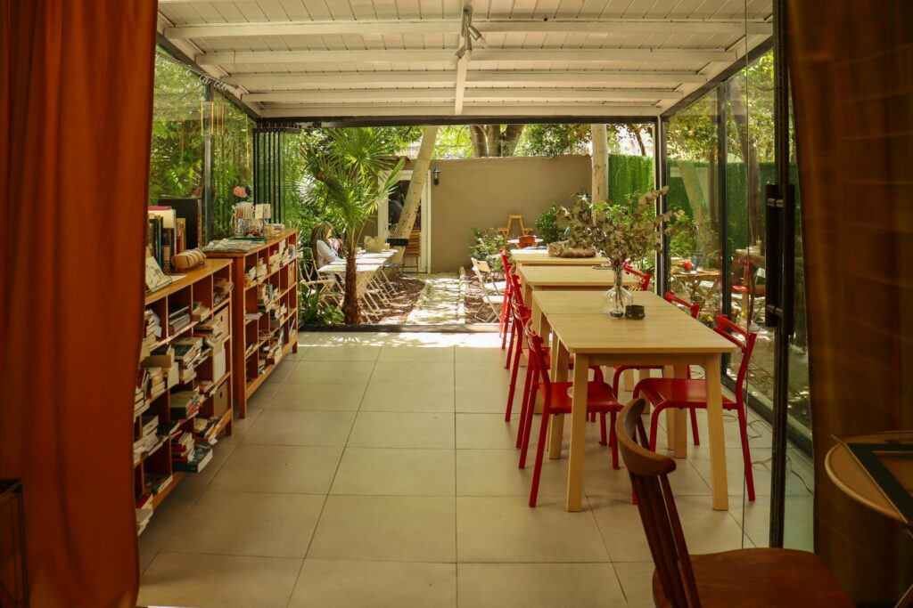 Inviting indoor-outdoor space with bookshelves, tables, and garden view, perfect for relaxation.