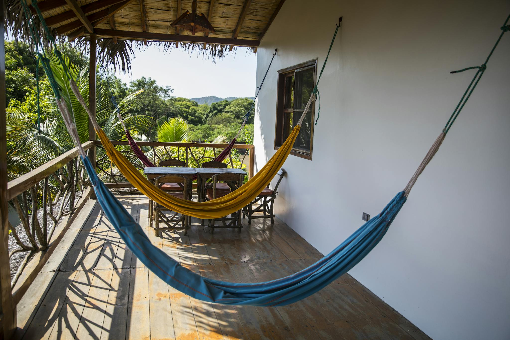 Relaxing tropical balcony view with vibrant hammocks and lush greenery in Brazil.